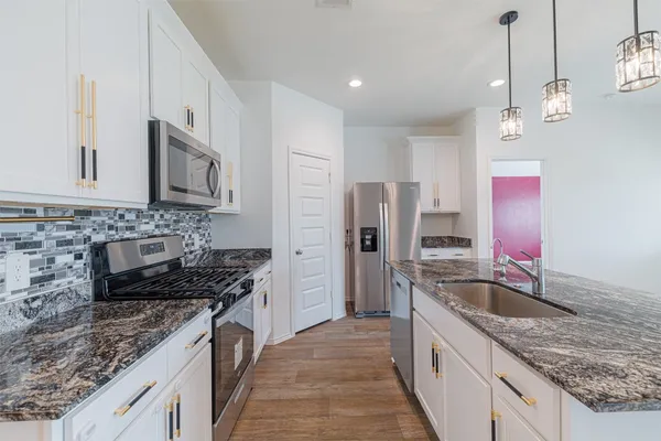 a kitchen with stainless steel appliances granite countertop a sink stove and refrigerator