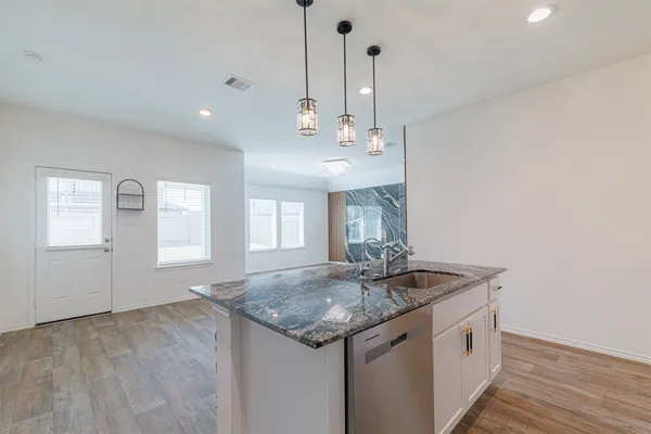 a kitchen with granite countertop cabinets and wooden floor