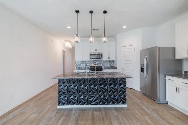 a kitchen with stainless steel appliances granite countertop a refrigerator a oven a stove and a wooden floors