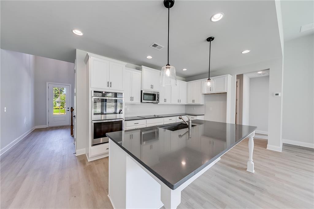 114 Classic Overlook Homer, GA 30547 - Photo 15 of 39 a kitchen with stainless steel appliances granite countertop a refrigerator a sink dishwasher a oven a dining table and chairs with wooden floor