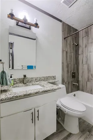a bathroom with a granite countertop sink mirror vanity and toilet