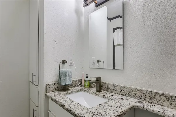 a bathroom with a granite countertop sink and a mirror