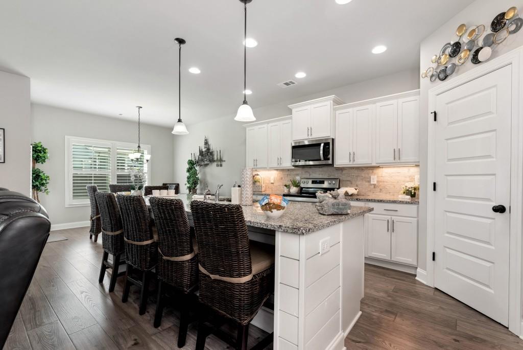 1311 Calgary Lake Drive Winder, GA 30680 - Photo 13 of 45 a kitchen with kitchen island granite countertop a sink cabinets and wooden floor