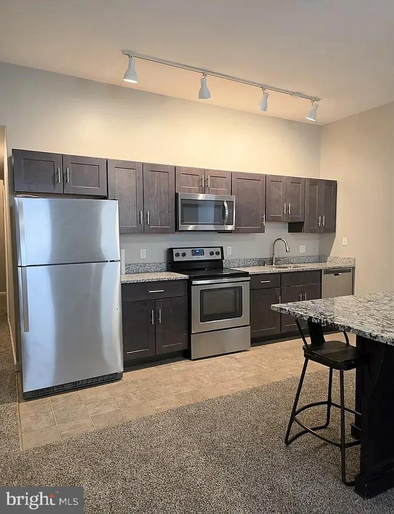 2128 Fleet Street, Unit 1 Baltimore, MD 21231 - Photo 1 of 11 a kitchen with stainless steel appliances granite countertop a refrigerator a stove a sink and a microwave
