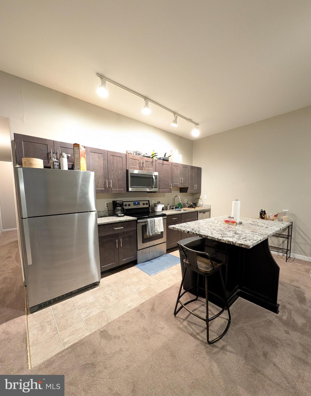 2128 Fleet Street, Unit 1 Baltimore, MD 21231 - Photo 2 of 11 a kitchen with stainless steel appliances a refrigerator a sink a stove a dining table and chairs