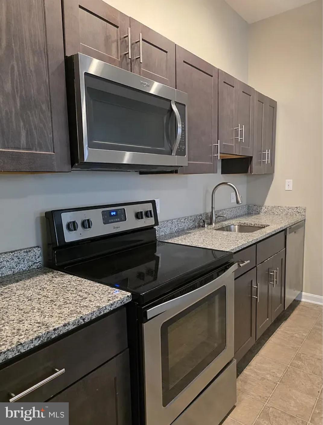 2128 Fleet Street, Unit 1 Baltimore, MD 21231 - Photo 3 of 11 a kitchen with granite countertop a stove microwave and sink
