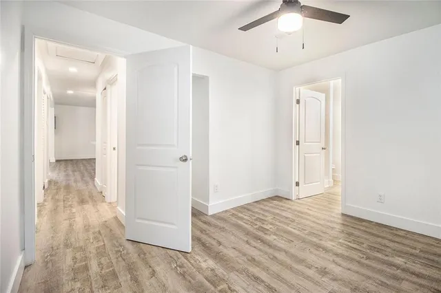 an empty room with wooden floor and ceiling fan