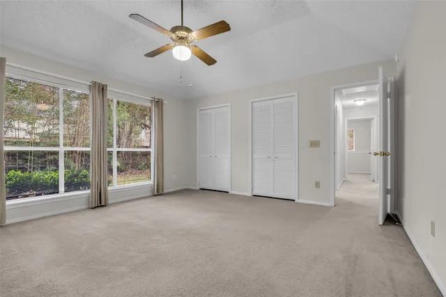 an empty room with chandelier fan and windows