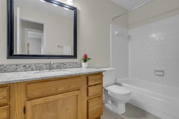 a bathroom with a granite countertop sink toilet and mirror