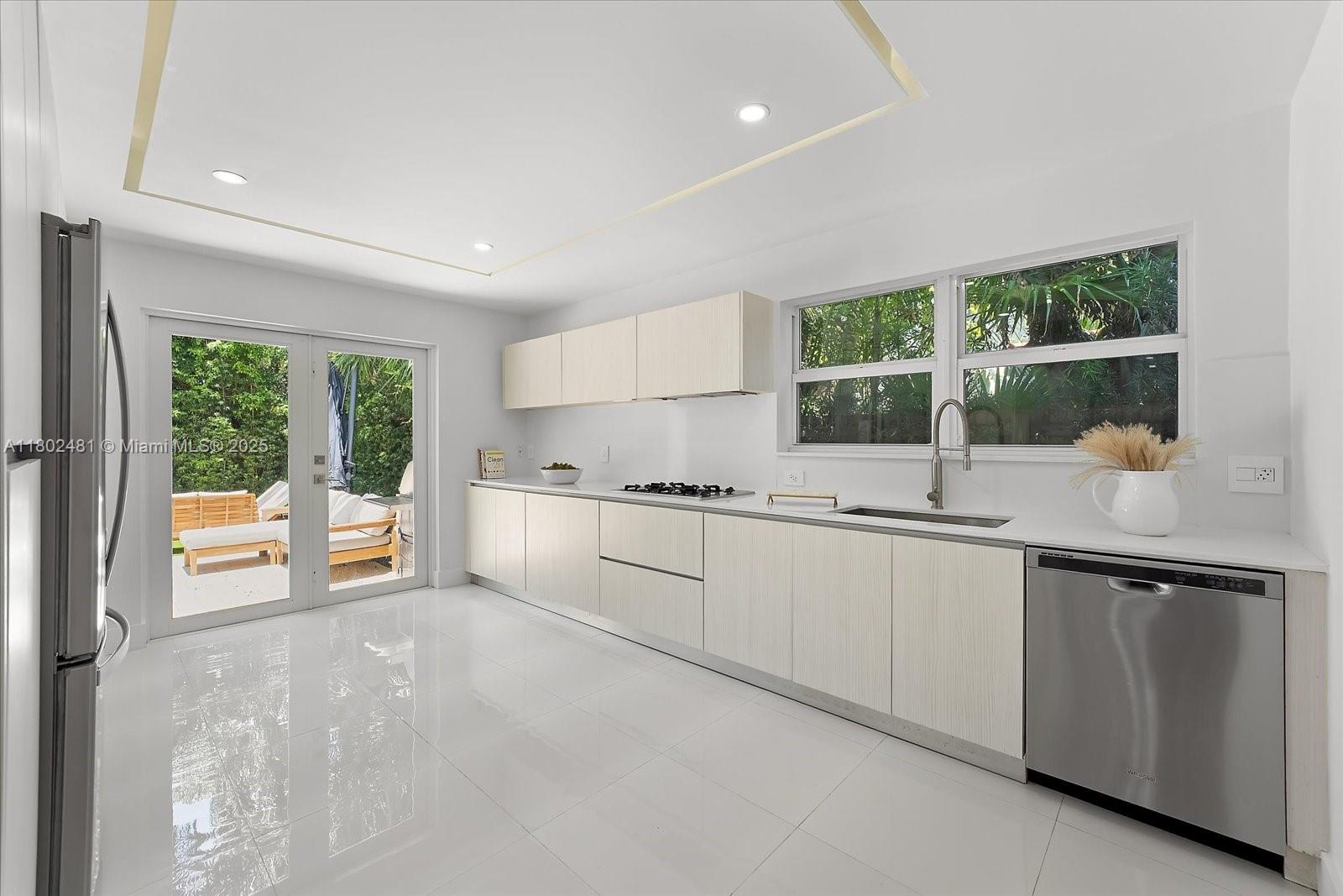3020 Alton Road Miami Beach, FL 33140 - Photo 13 of 40 a kitchen with granite countertop a sink and white cabinets with wooden floors