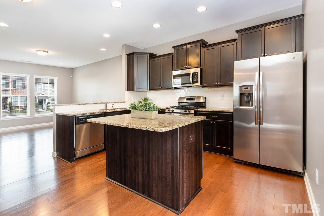 421 Provincial Street Raleigh, NC 27603 - Photo 4 of 22 a kitchen with stainless steel appliances granite countertop a refrigerator a sink dishwasher a stove with wooden cabinets and wooden floor