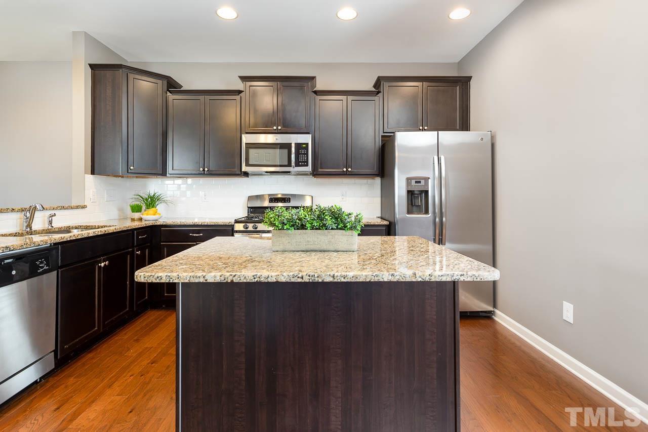 421 Provincial Street Raleigh, NC 27603 - Photo 5 of 22 a kitchen with kitchen island granite countertop stainless steel appliances a sink a refrigerator and a counter