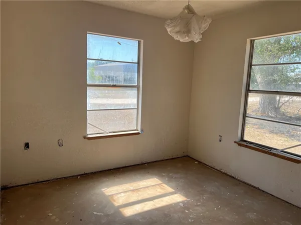 an empty room with windows and chandelier
