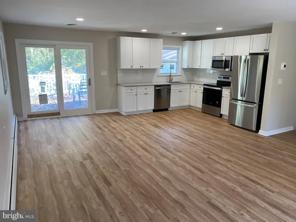 a view of kitchen with kitchen island wooden floors appliances and cabinets