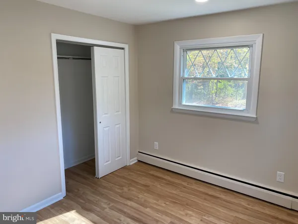 an empty room with wooden floor closet and windows