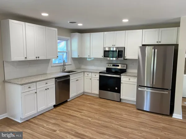 a kitchen with a refrigerator a sink and dishwasher with wooden floor