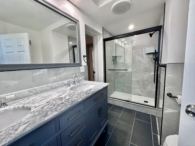 a bathroom with a granite countertop sink mirror and shower