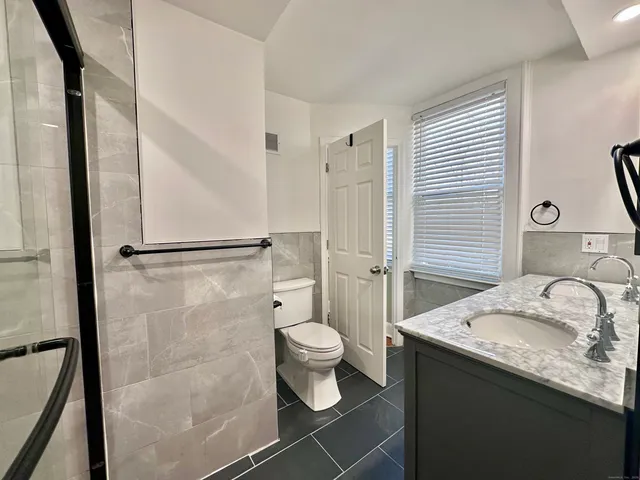 a bathroom with a granite countertop sink a toilet and shower