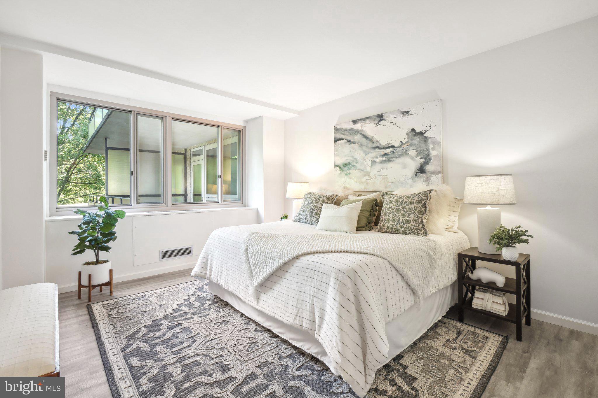 4101 Cathedral Avenue Northwest, Unit 306 Washington, DC 20016 - Photo 9 of 31 a spacious bedroom with a large bed and a potted plant
