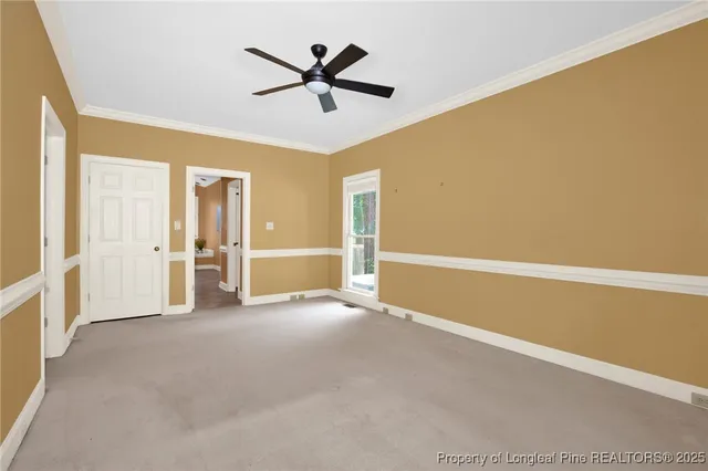 an empty room with ceiling fan and windows