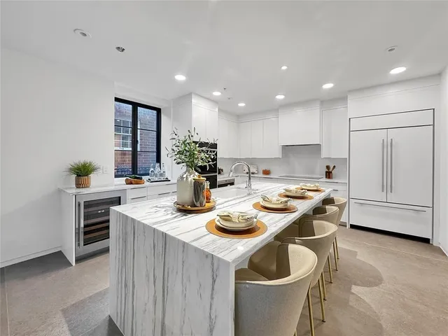 a kitchen with stainless steel appliances granite countertop a sink a stove a refrigerator and white cabinets with wooden floor