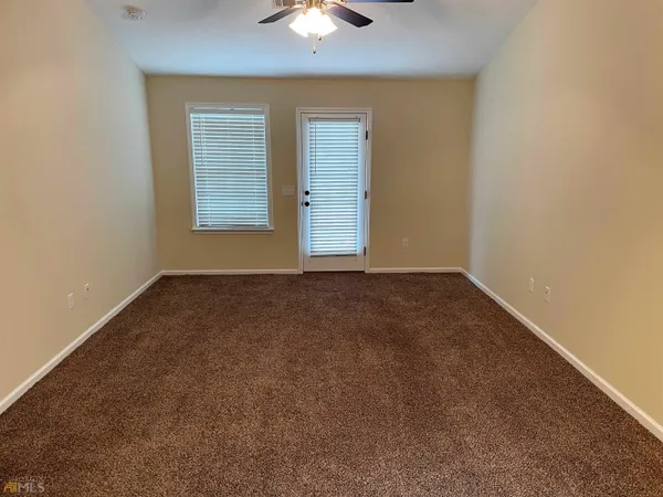 an empty room with a chandelier fan and windows