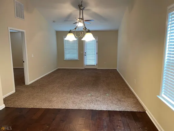 an empty room with wooden floor windows and entrance