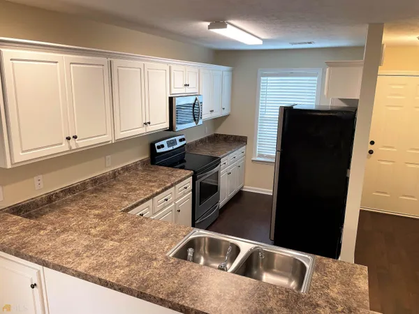 a kitchen with granite countertop a refrigerator and a sink
