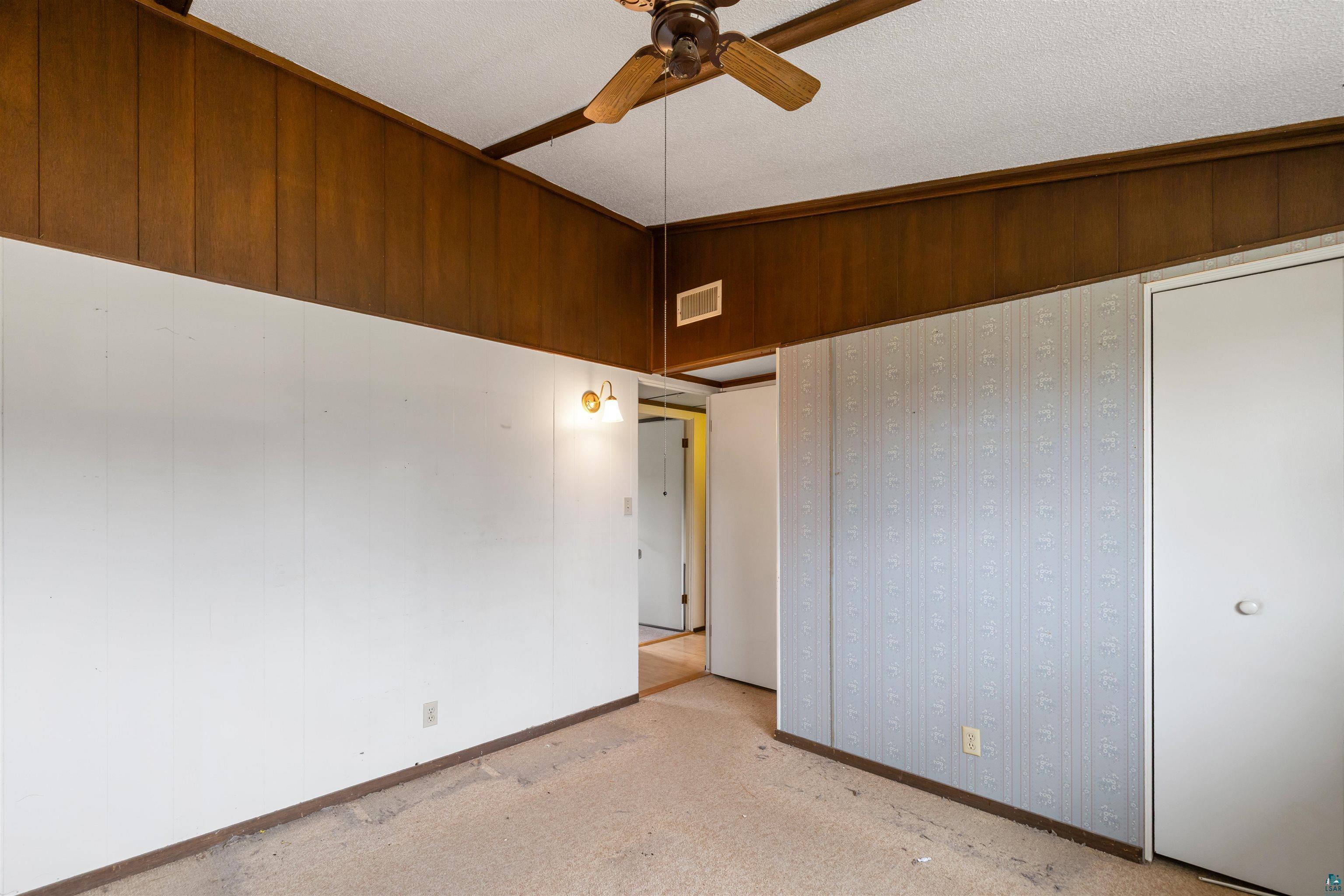 11574 Town Line Road Hibbing, MN 55746 - Photo 13 of 41 Room featuring wood-paneled ceiling trim, a ceiling fan with wood-finish blades, textured white ceilings, and a combination of white and patterned wall finishes