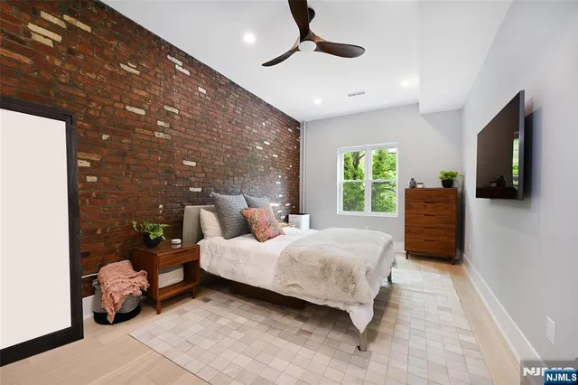 a bedroom with a bed a couch and a flat tv screen on dresser