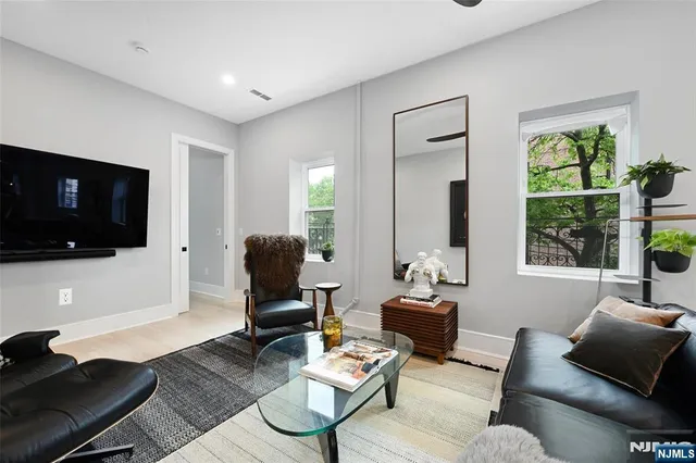 a living room with furniture a flat screen tv and a window