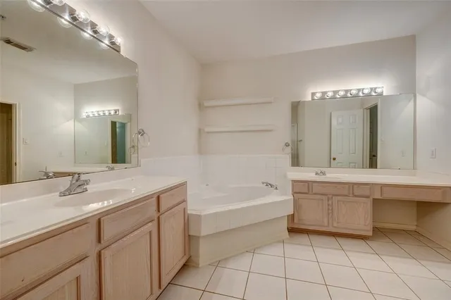 a bathroom with a tub a sink and a mirror