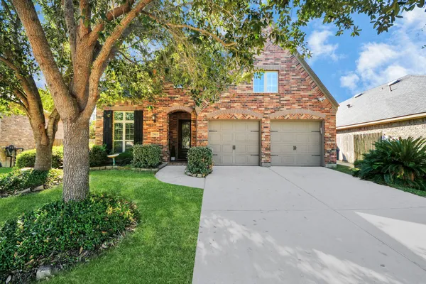 front view of house with a yard and trees all around