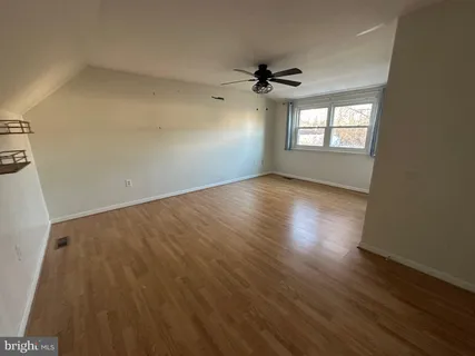a view of empty room with wooden floor and fan