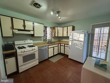 a kitchen with stainless steel appliances granite countertop a sink a stove a refrigerator with grey cabinets