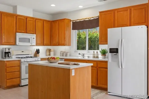 a kitchen with stainless steel appliances granite countertop a refrigerator a sink a stove with wooden cabinets
