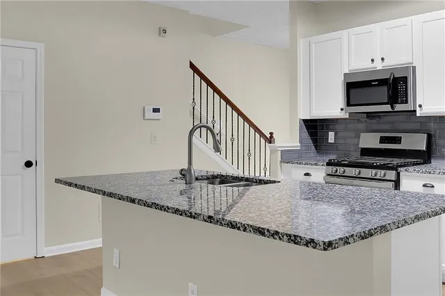 a kitchen with granite countertop a sink and a stove top oven