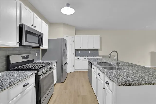 a kitchen with stainless steel appliances granite countertop a sink stove microwave and refrigerator