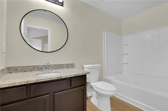 a bathroom with a granite countertop toilet a sink and a mirror