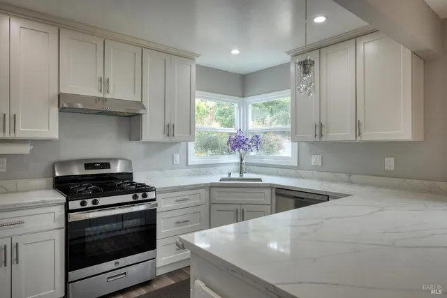 a kitchen with stainless steel appliances a sink a stove a refrigerator cabinets and a counter space