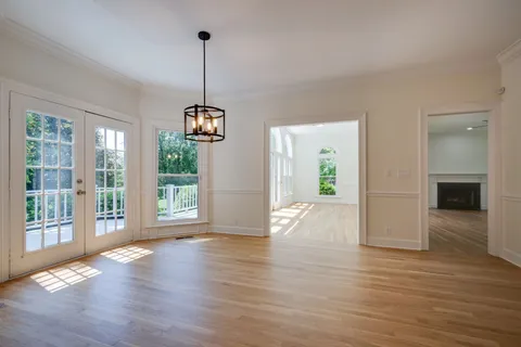 a view of a room with wooden floor a ceiling fan and windows