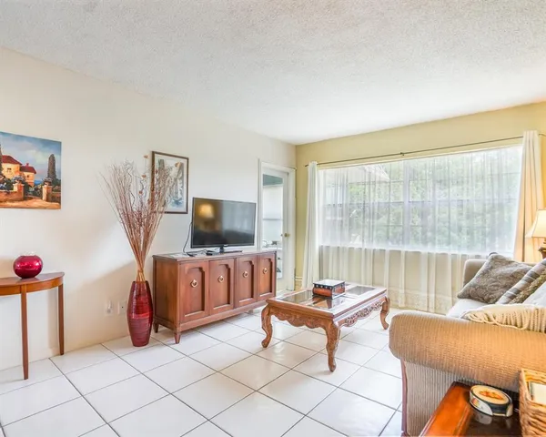 a living room with furniture a flat screen tv and floor to ceiling window