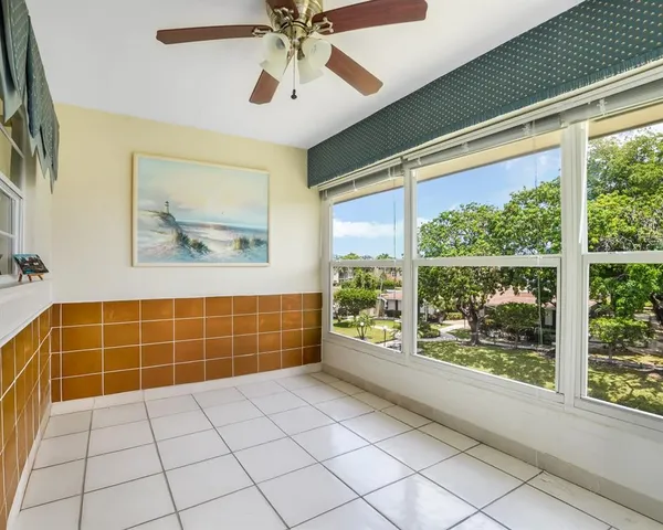 a view of an empty room with a window and chandelier fan