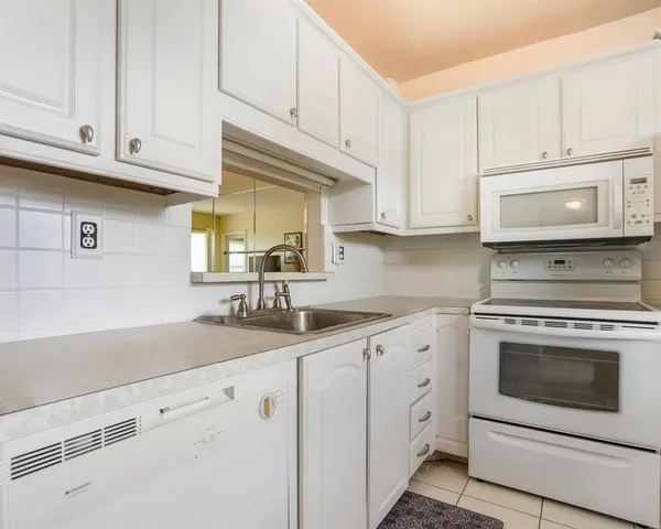 a kitchen with granite countertop white cabinets white stainless steel appliances and a sink