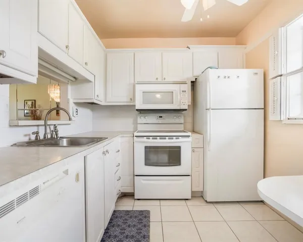 a white refrigerator freezer sitting inside of a kitchen with white cabinets