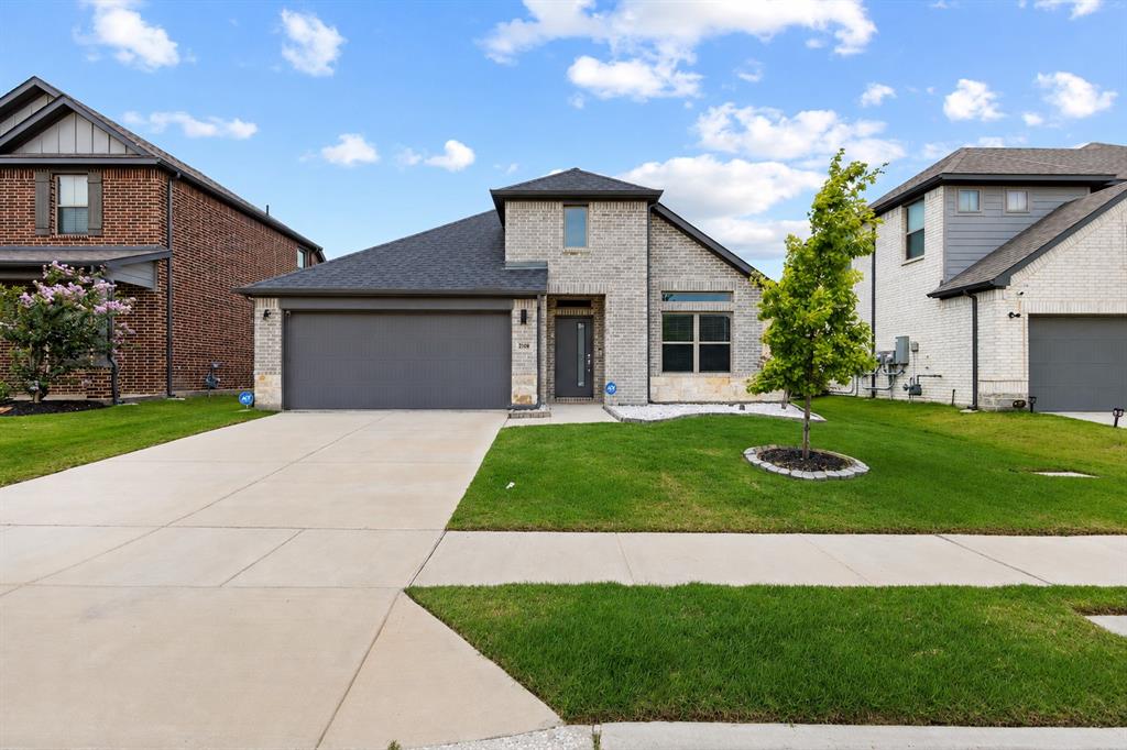 2108 Mossfield Lane Forney, TX 75126 - Photo 11 of 28 Contemporary single-story residence featuring light-colored brick and stone facade, a dark shingle roof, and an attached two-car garage with a dark gray door