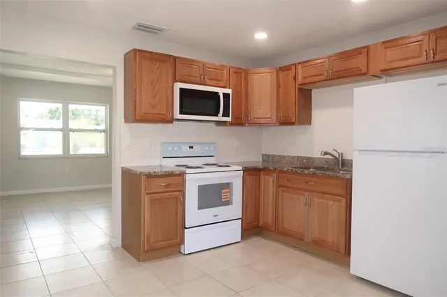 a kitchen with stainless steel appliances granite countertop a stove top oven a sink and a refrigerator