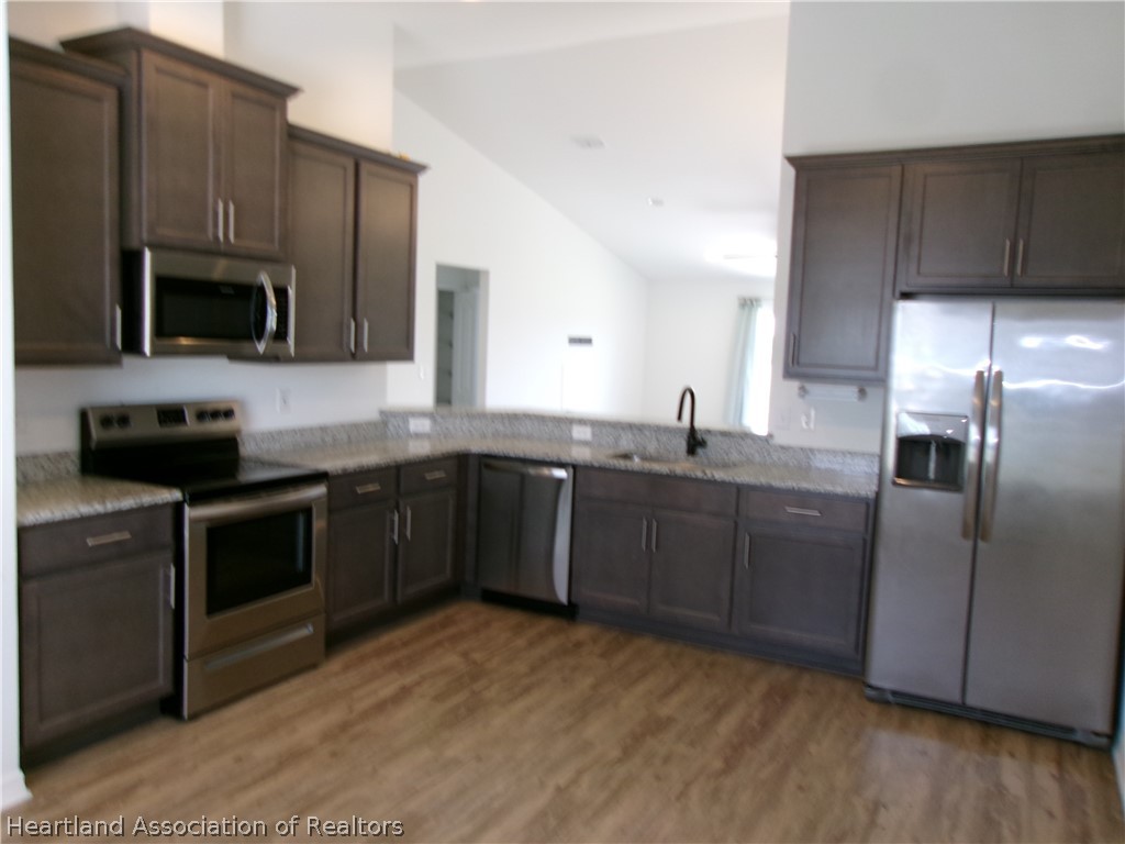 512 Central Ridge Lane Frostproof, FL 33843 - Photo 8 of 19 a kitchen with cabinets stainless steel appliances and wooden floor
