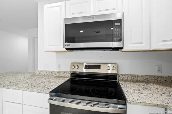 a kitchen with granite countertop a stove and a microwave