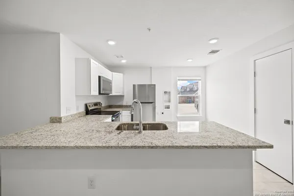 a kitchen with granite countertop kitchen island stainless steel appliances refrigerator sink and stove